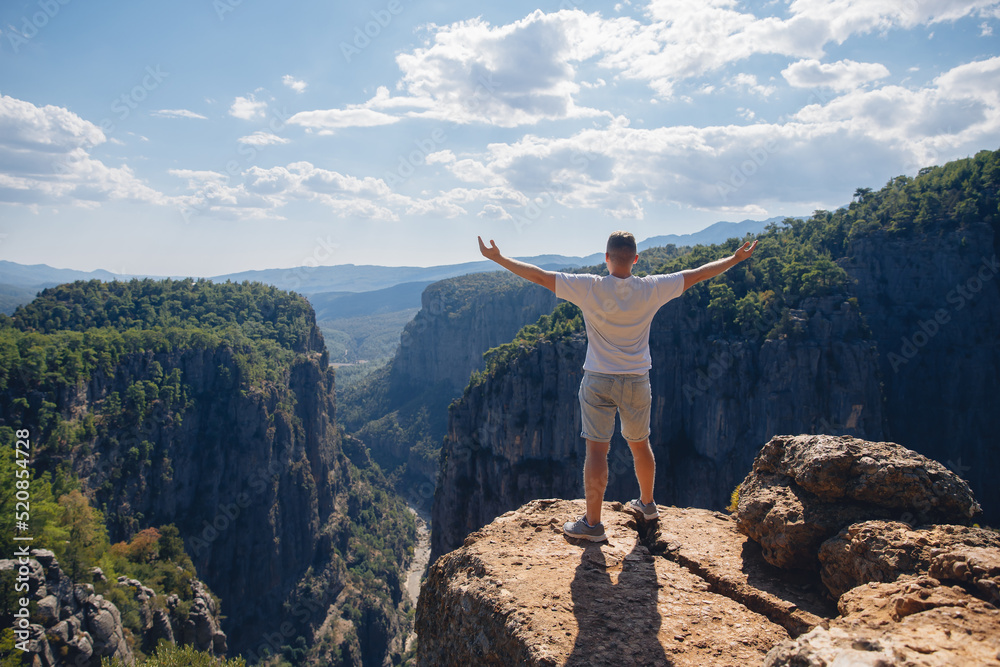 Happy man stands with raised hands on background mountain Tazi Canyon in Manavgat Antalya Turkey