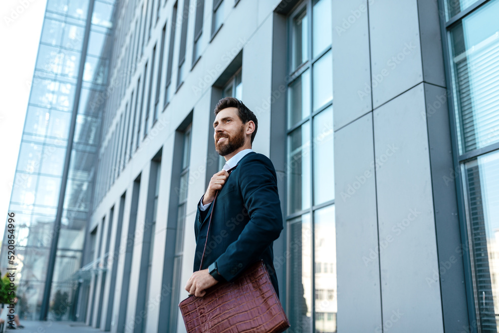 Happy confident handsome millennial european businessman with beard in suit with bag looks at free space Happy confident handsome millennial european businessman with beard in suit with bag looks at free space