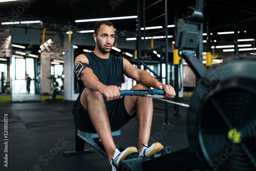 Photographie Sporty Young Black Man Exercising With Rowing Machine At Modern Gym