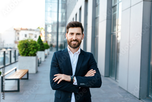 Leadership, ceo manager and boss. Smiling confident young attractive european man with beard in suit with crossed arms photo