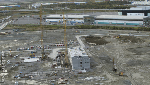 Top view of construction site in countryside. Stock footage. Construction site in city on sunny summer day. Crane and trucks at construction site near city photo