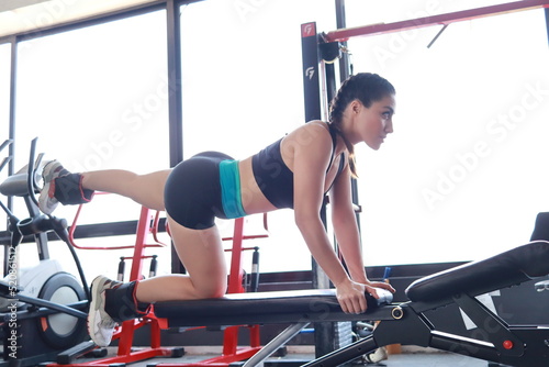 Girl in the gym using leg dumbbells 