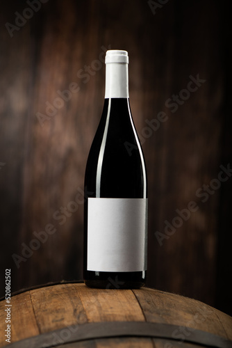 A Red wine bottle on wodden barrel with a wooden backgorund