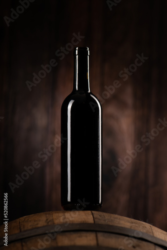 A Red wine bottle on wodden barrel with a wooden backgorund