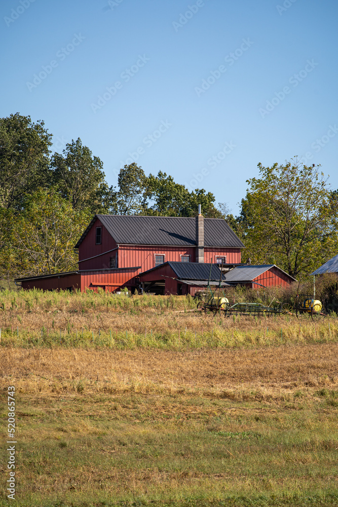 Red barn on a hill with trees in the background under a blue sky | Amish country in Holmes County, Ohio