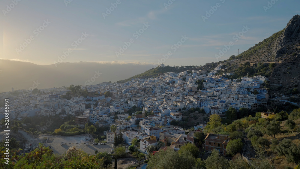 Bird's-eye view.Action. A beautiful landscape and a view of the city with small houses which is located on the mountains with green trees against the blue sky.