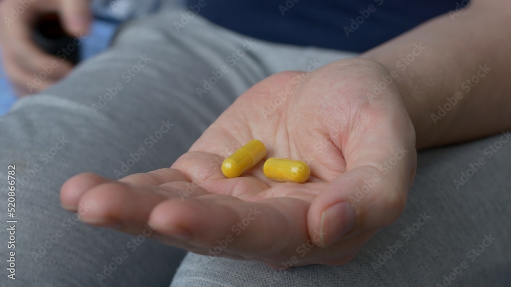 Two gelatin capsules with medicines are poured into the palm of your hand. Yellow capsules with drugs for the treatment of serious diseases. The high price of drugs and medicines. Two gelatin capsules with medicines are poured into the palm of your hand. Yellow capsules with drugs for the treatment of serious diseases. The high price of drugs and medicines.