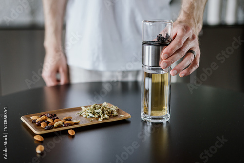 man brewing herbal tea in infuser or glass travel bottle