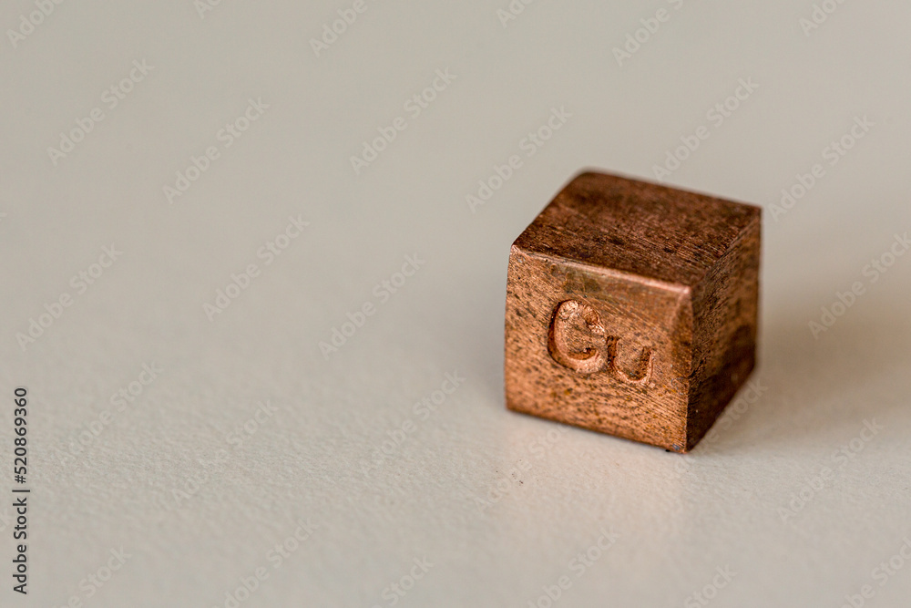 Copper cube with element name Cu on it on cream background Copper cube with element name Cu on it on cream background