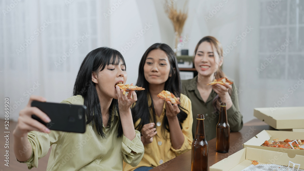 Holiday concept of 4k Resolution. Group of Asian female friends inviting online friends to eat pizza together at home. Fun and exciting leisure activities. Holiday concept of 4k Resolution. Group of Asian female friends inviting online friends to eat pizza together at home. Fun and exciting leisure activities.