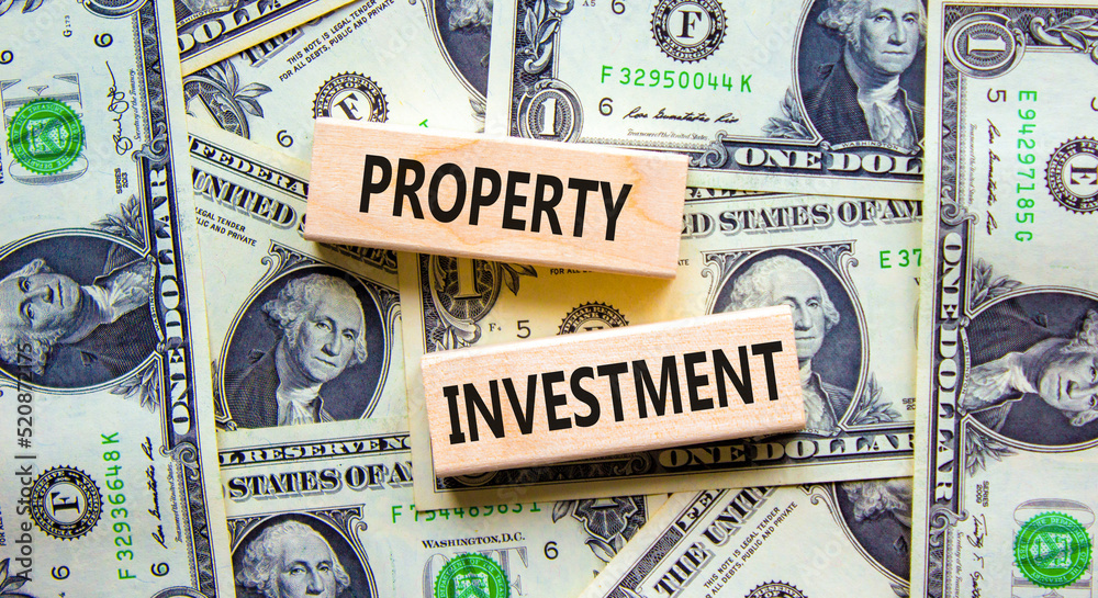 Property investment symbol. Concept words Property investment on wooden blocks on a beautiful background from dollar bills. Business Property investment concept. Copy space.