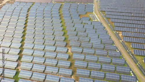 Solar power station in Greenfield on a sunny day. aerial view Solar panels line up in the field for power generation Drone flying over Solar Farm Green Energy Landscape Electricity Ecology Innovation