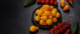 Pear-shaped small yellow tomatoes in a ceramic plate on a dark concrete table
