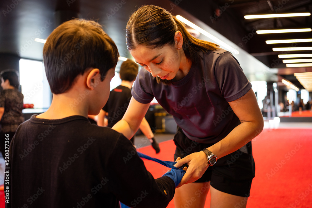 female instructor placing bandage on boy in gym