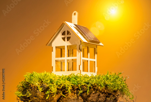 Eco housing concept,  toy house with solar panel on roof on land plot with green grass
