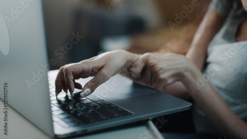 Close shot of the hands of a woman with spinal muscular atrophy surfing the Internet or social media typing on a laptop keyboard