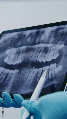 A dentist shows a patient a picture of teeth using a tablet photo