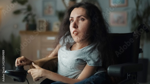 Obraz na plátně Frustrated woman with spinal muscular atrophy sitting in a wheelchair in a dim l
