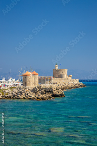 Windmills of Mandraki harbour and Saint Nicholas Fortress in Rhodes town, Greece, Europe.