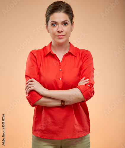 Serious young lady standing with arms crossed. Confident woman in red shirt isolated portrait.