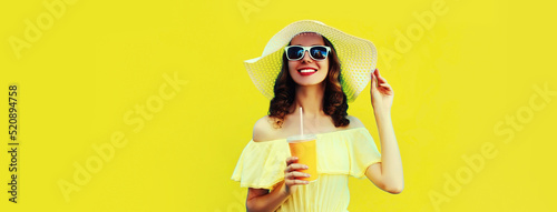 Portrait of beautiful young woman drinking fresh juice wearing white summer straw hat on yellow background © rohappy