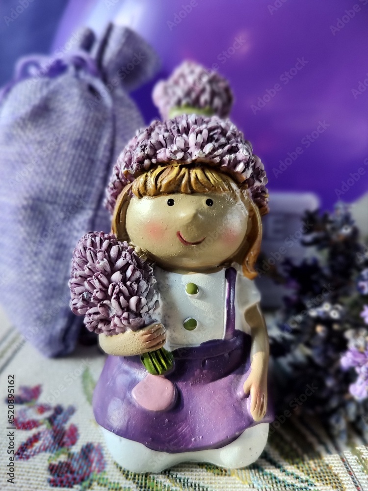 Ceramic figurine of a girl with lavender on a lavender tablecloth on a purple background