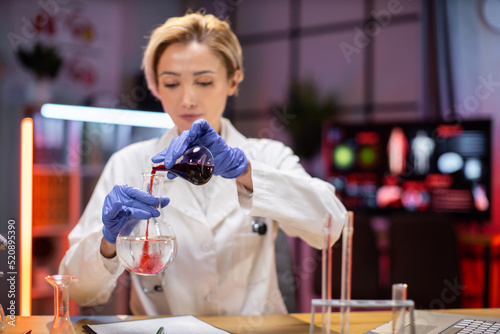 Focus on test tube. Scientific innovations. Positive smart enthusiastic woman scientist looking at the test tubes and smiling while developing a vaccine.