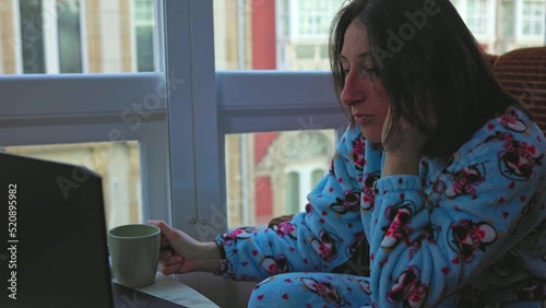 Billede på lærred a girl in blue pajamas sits by the window behind a nautbook and cries