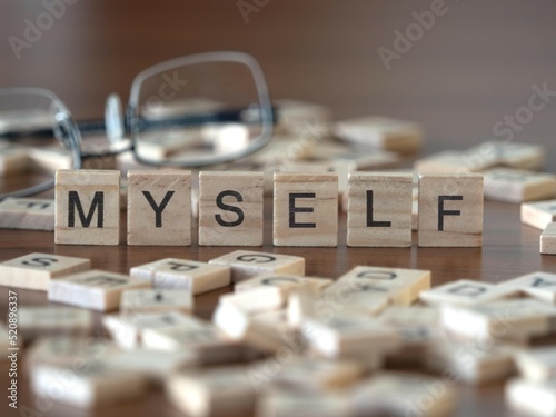 myself word or concept represented by wooden letter tiles on a wooden table with glasses and a book
