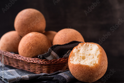 Round colombian traditional food named buñuelo in a basket on black wooden table  photo