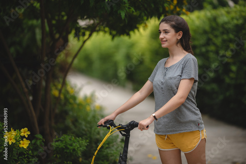 Carefree and young woman relaxing and enjoying while exercising on cycle outdoor
