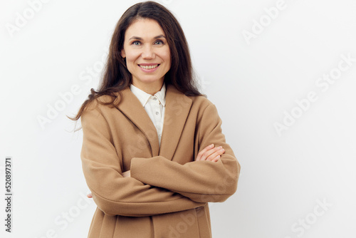 portrait of a pleasant cute woman in a stylish beige warm coat with her arms crossed on her chest