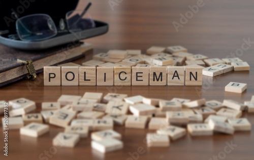 policeman word or concept represented by wooden letter tiles on a wooden table with glasses and a book photo