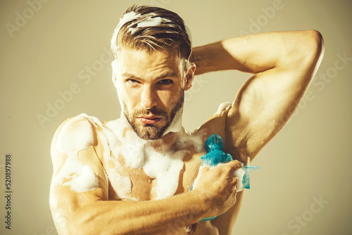 Sexy man washing body in bathroom. Handsome unshaven macho with strong muscles taking shower.