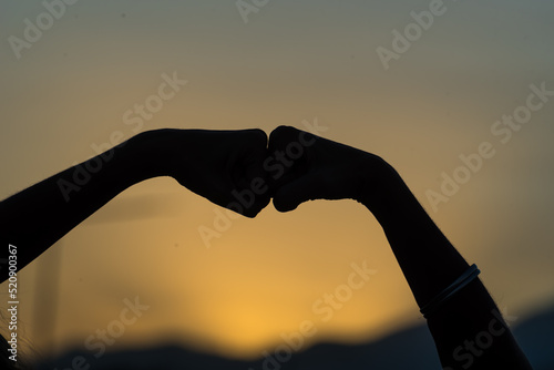 person making silhouettes with their hands in the darkness of a sunset
