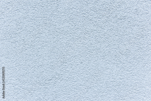 Pastel blue plaster on rough concrete stone surface with tiny dots. Cement and sand texture of wall in light color as background extreme closeup
