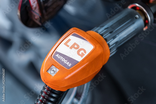 Close-up detail view of fuel autogas pump gun connected with noozle adapter to car tank to refill at car gas filling station. Refueling vehicle with liquefied lpg or lng product. Safety technology