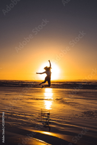 Silhouette of a person on the beach at sunset with reflection