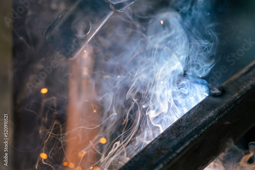 Welding close-up, a lot of sparks and smoke from electronic welding, industrial area