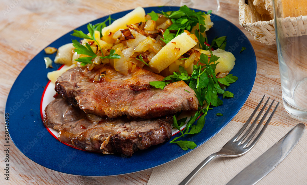 Appetizing pork steaks with side dish of boiled potatoes with fried onion and fresh greens