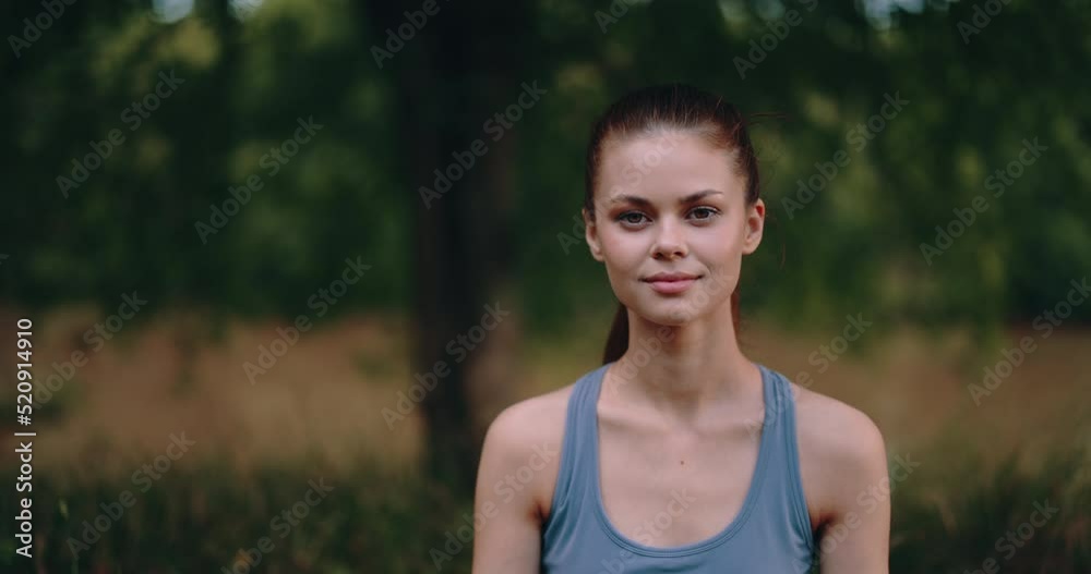 Close-up portrait of a woman smiling and looking at the camera in nature in the park after a workout Close-up portrait of a woman smiling and looking at the camera in nature in the park after a workout