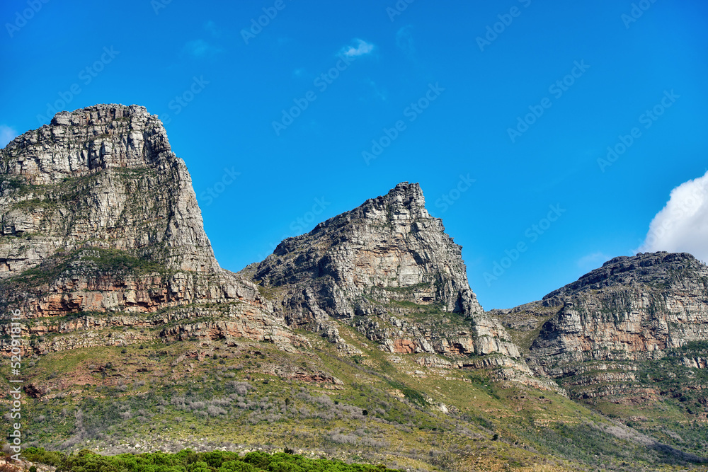 Beautiful outdoor mountain landscape with a blue sky copyspace in nature. Outside view of high mountains, green grass, and plant life. Relaxing natural background of rock formations on a summer day