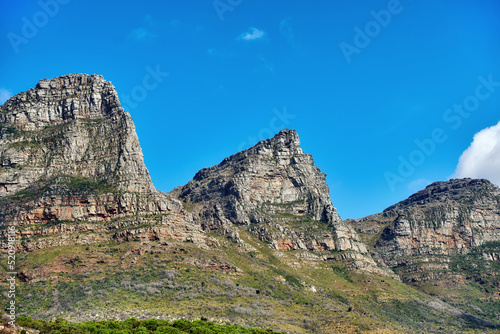 Beautiful outdoor mountain landscape with a blue sky copyspace in nature. Outside view of high mountains, green grass, and plant life. Relaxing natural background of rock formations on a summer day
