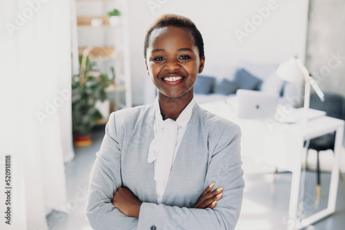 Portrait of a successful african-american business woman standing with crossed arms, looking at the camera. Beautiful young girl. Closeup portrait. Positive