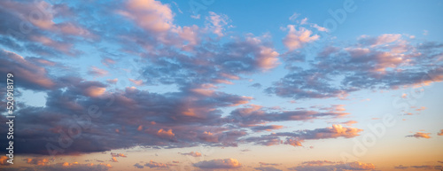 Obraz na płótnie Evening blue sky and gray clouds with orange and pink highlights reflecting setting or rising sun, at dusk or dawn. w salonie