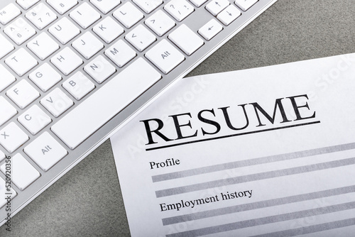 Resume and keyboard on the table closeup.