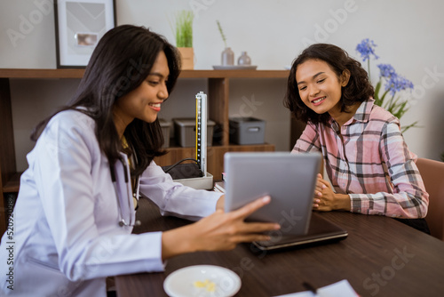 doctor showing tablet screen to patient during consultation in clinic room