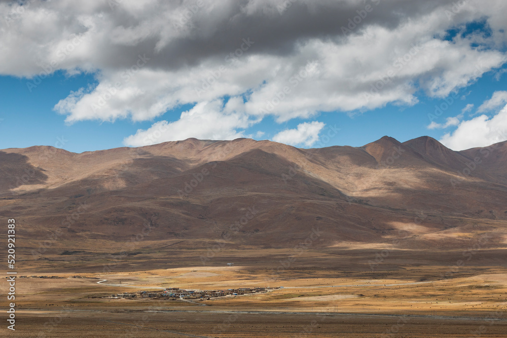 Panoramic landscape in Tibet with a remote village and mountains on background