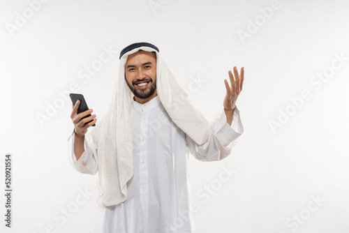excited young man in a turban using a mobile phone happily looking at the screen with an excited expression on a plain background © Odua Images