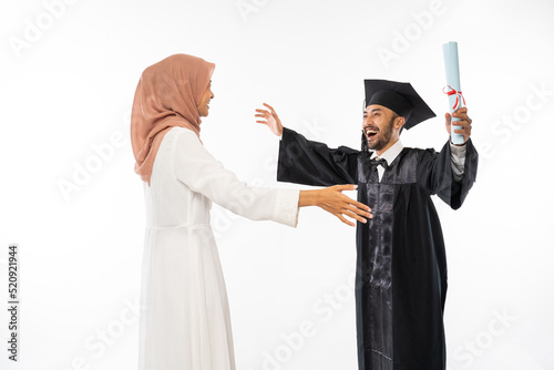 Happy graduate male student wearing toga holding roll certificate will hug his lover on isolated background photo